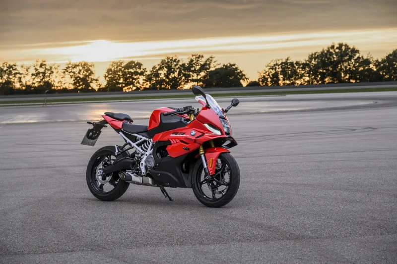 BMW F 450 RR roja estacionada sobre el asfalto de un circuito al atardecer
